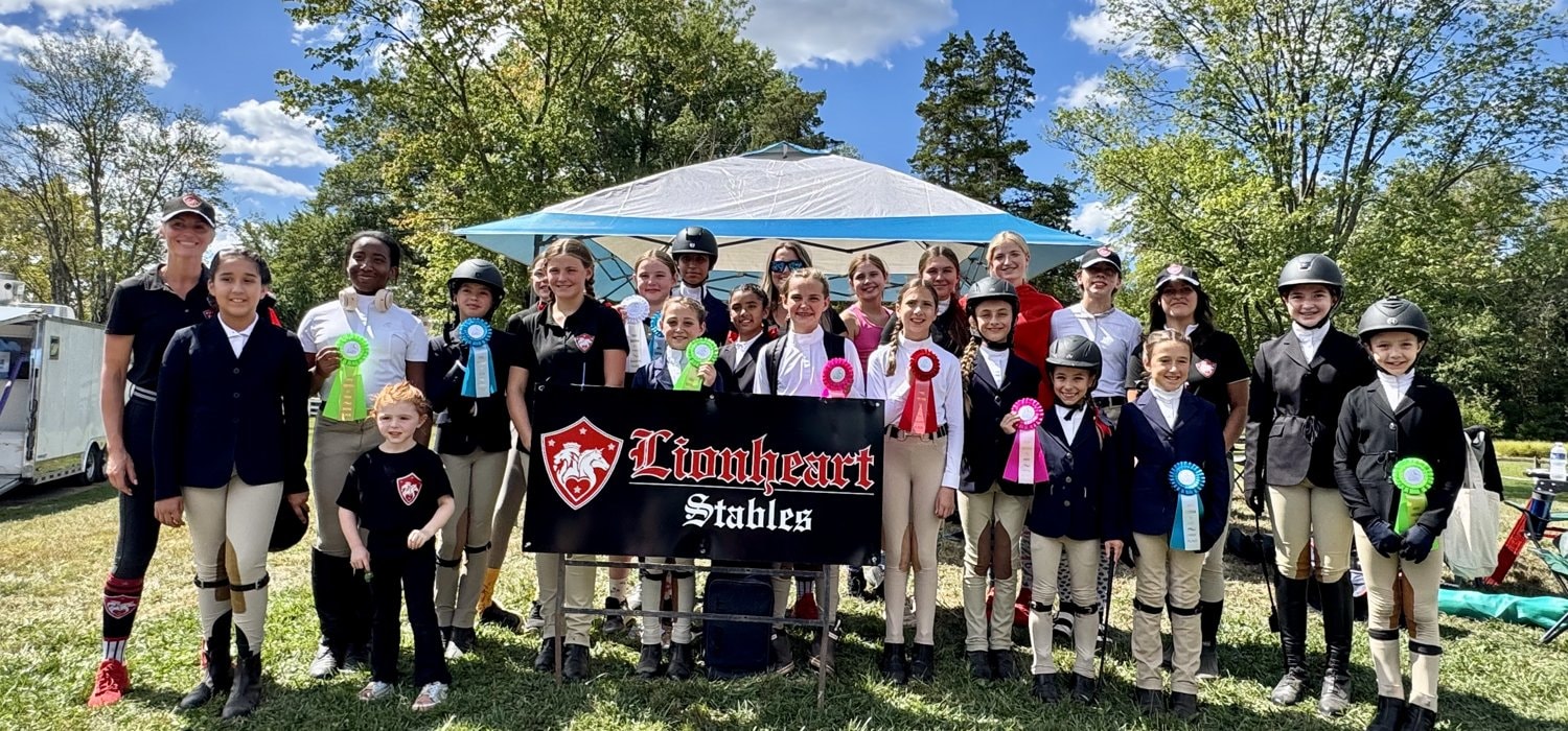 Lionheart Stables riders and staff celebrating at an equestrian event with ribbons